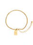 Delicate 18K gold-plated chain bracelet with Good Luck engraved rectangular pendant on cream background