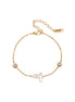 Gold chain bracelet with white mother of pearl butterfly pendant and two bezel-set crystals on cream background