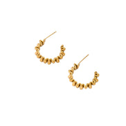 Sculptural gold-plated hoop earrings with continuous twisted spiral design on cream background