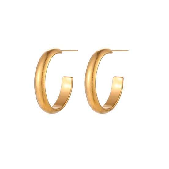Chunky tubular hoop earrings in warm 14K gold-plated finish with smooth polished surface on cream background.