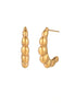 Gold-plated chunky hoop earrings with ridged bubble texture on cream background